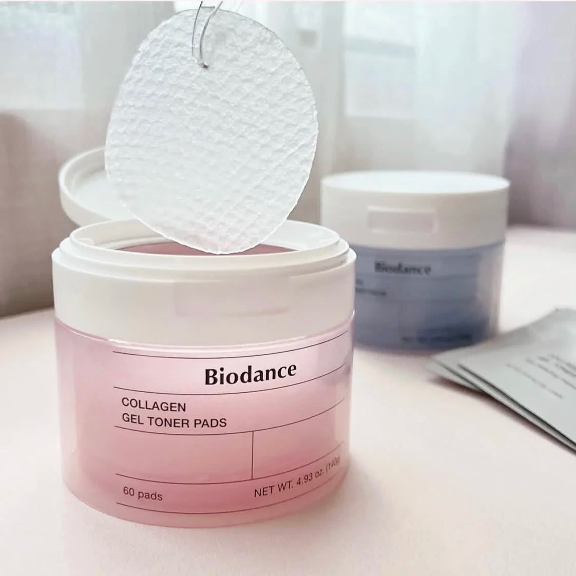 Biodance collagen gel toner pads in a pink container on a white surface.